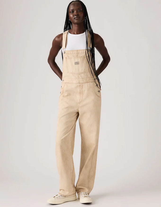 Person wearing beige overalls on a white background. Vintage Overall Cloudy Travertine