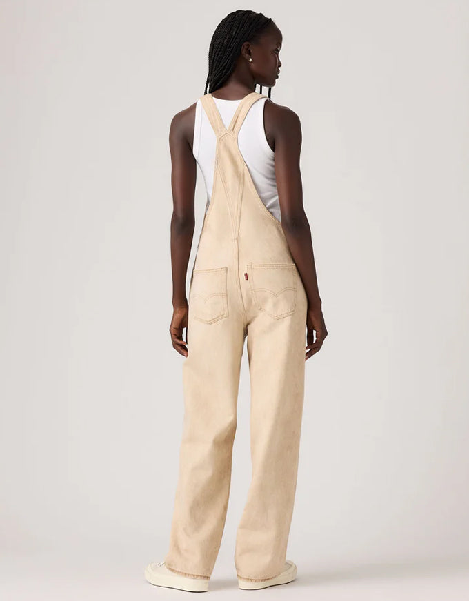 Person wearing beige overalls on a plain background. Vintage Overall Cloudy Travertine