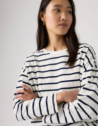 Woman wearing a white and navy striped shirt against a plain background