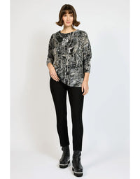 Woman wearing a patterned top and black pants on a white background