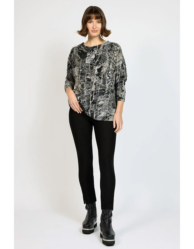 Woman wearing a patterned top and black pants on a white background