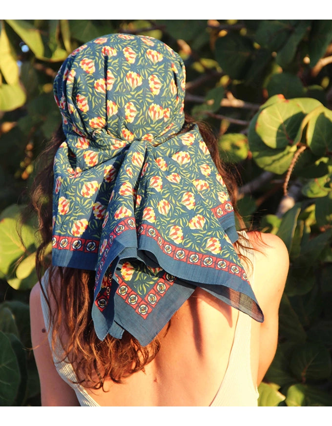 Person wearing a floral patterned headscarf with greenery in the background
