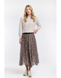 Woman wearing a light gray sweater and patterned skirt on a white background