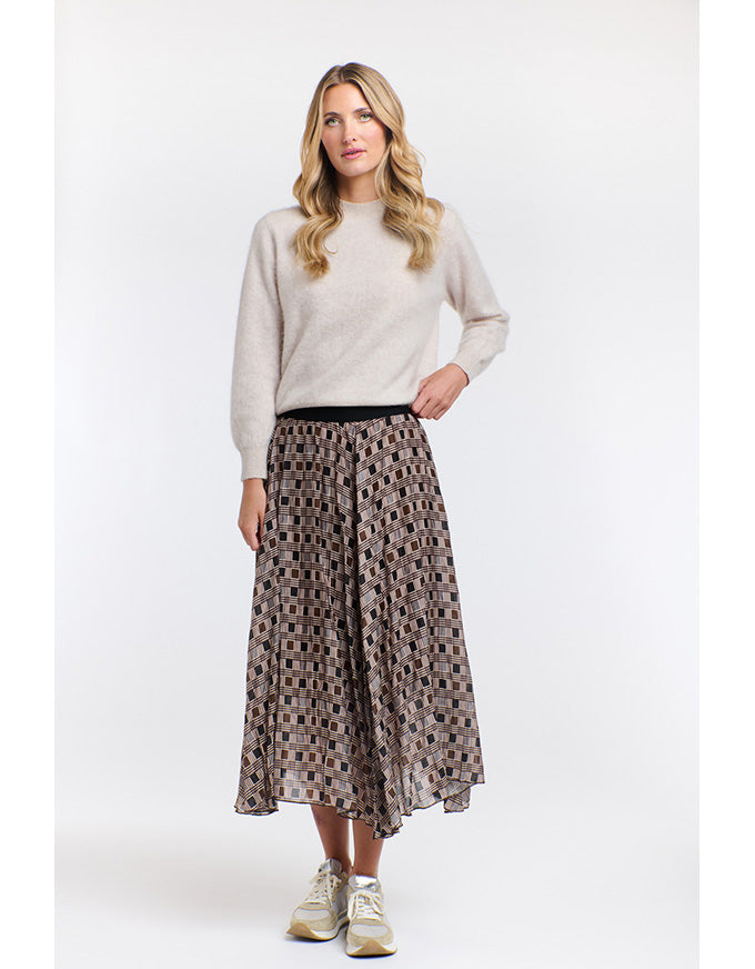 Woman wearing a light gray sweater and patterned skirt on a white background