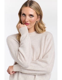 Woman wearing a beige sweater against a white background