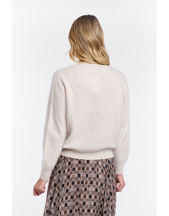 Woman wearing a beige sweater and plaid skirt on a white background