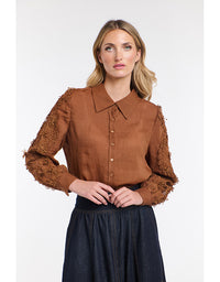 Woman wearing a brown blouse with lace sleeves on a white background