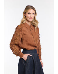 Woman wearing a brown blouse with lace sleeves on a white background