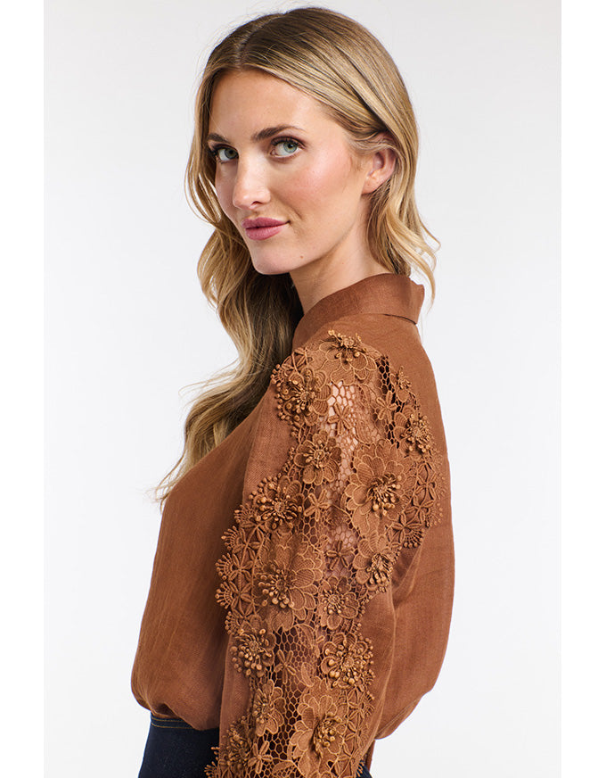 Woman wearing a brown blouse with floral lace details on a white background