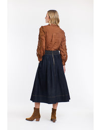 Woman wearing a brown blouse and dark blue skirt on a white background