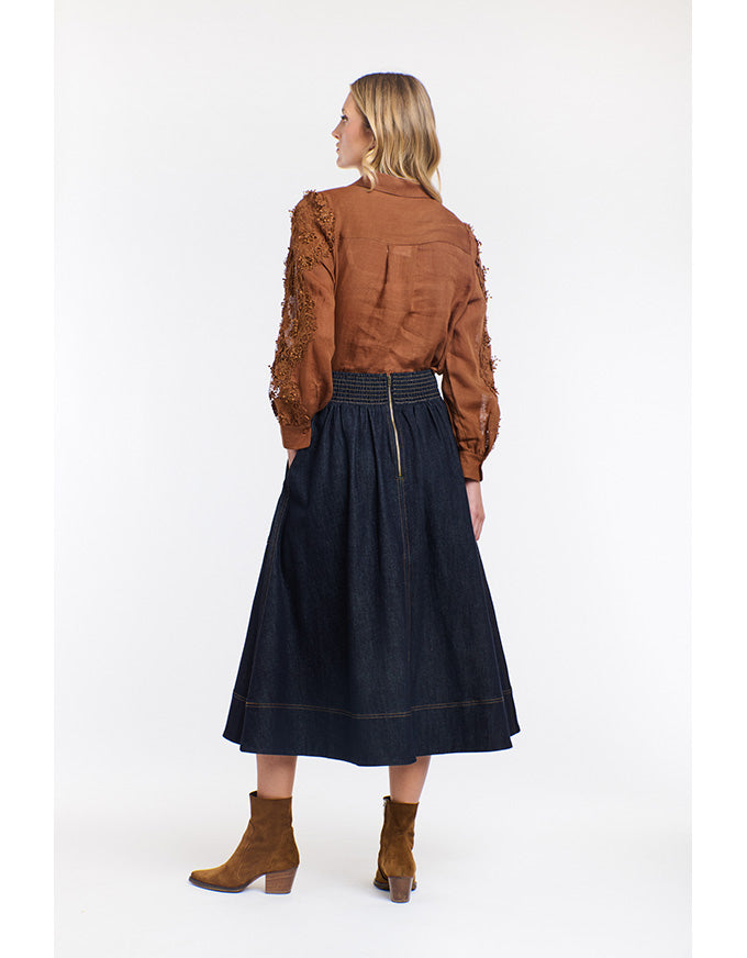 Woman wearing a brown blouse and dark blue skirt on a white background