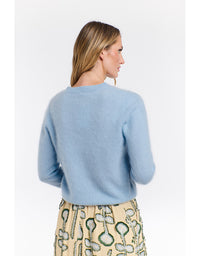 Woman wearing a light blue sweater and patterned pants on a white background