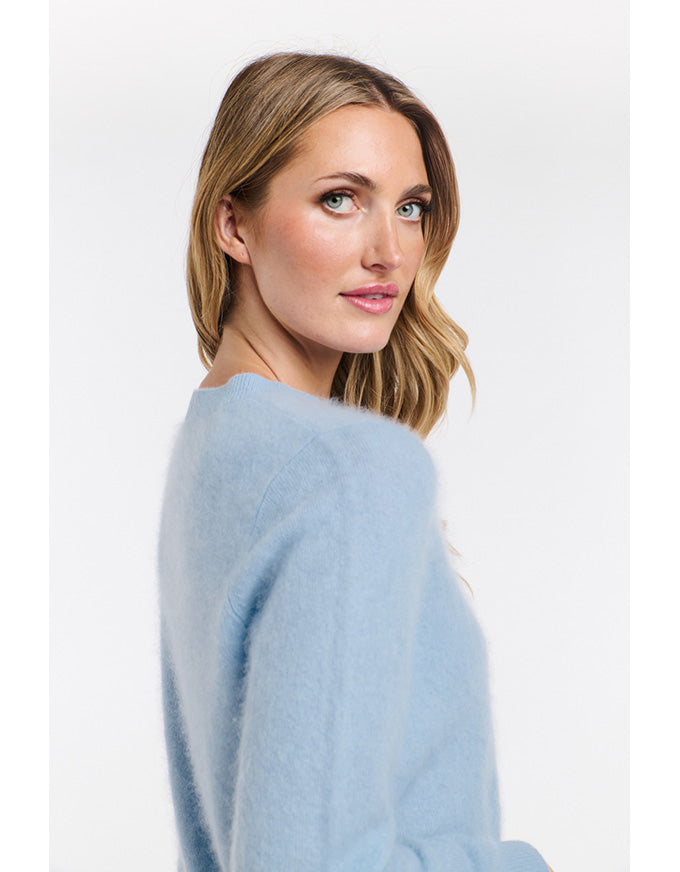 Woman wearing a light blue sweater against a white background