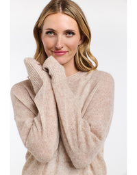 Woman wearing a beige sweater against a white background