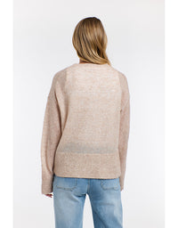 Person wearing a beige sweater and light blue jeans on a white background
