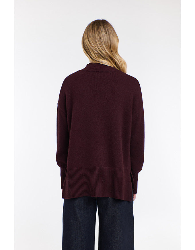 Person wearing a burgundy sweater on a white background