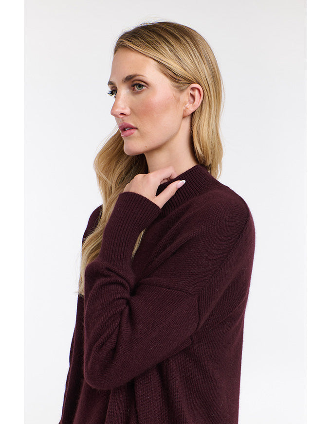 Woman wearing a burgundy sweater against a white background