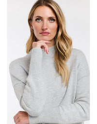 Woman wearing a light gray sweater on a white background