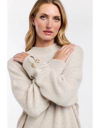 Woman wearing a beige sweater with a white background