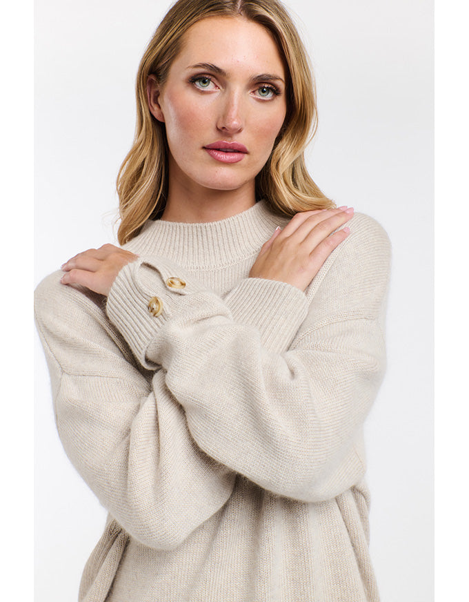 Woman wearing a beige sweater with a white background