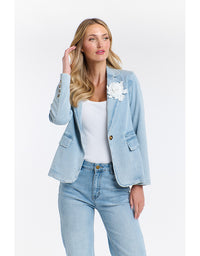 Woman wearing a light blue denim jacket with floral details on a white background