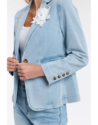 Light blue denim jacket with white flower accessory on a plain background