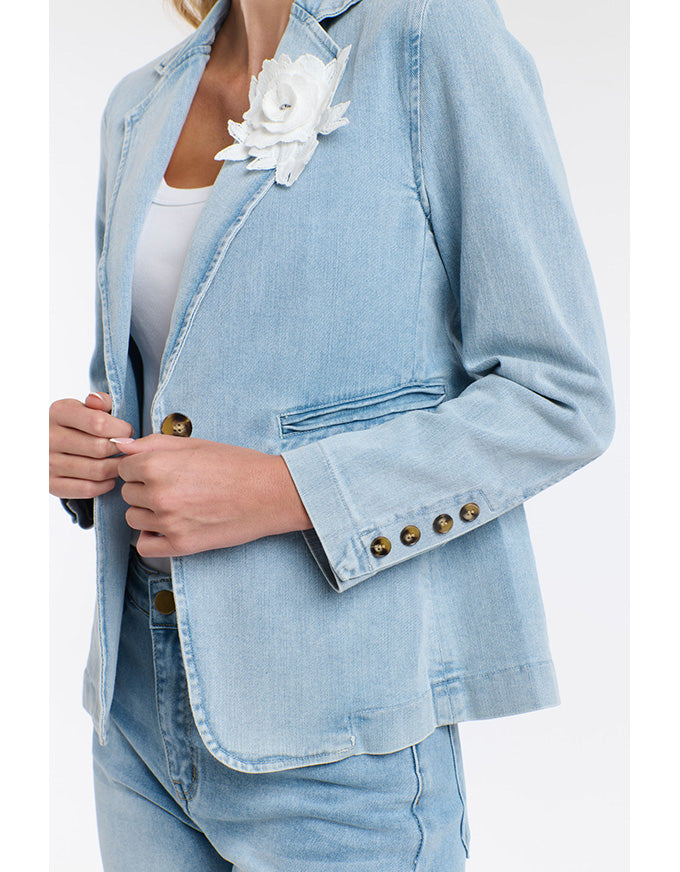 Light blue denim jacket with white flower accessory on a plain background