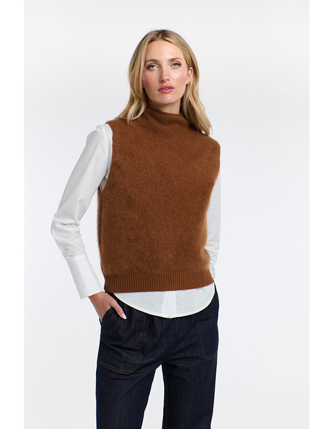 Woman wearing a brown sweater vest over a white shirt on a white background
