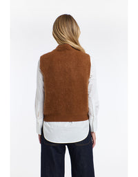 Person wearing a brown vest over a white shirt on a white background