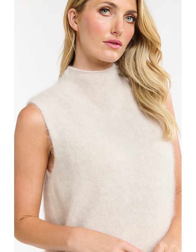 Woman wearing a beige sleeveless top against a white background