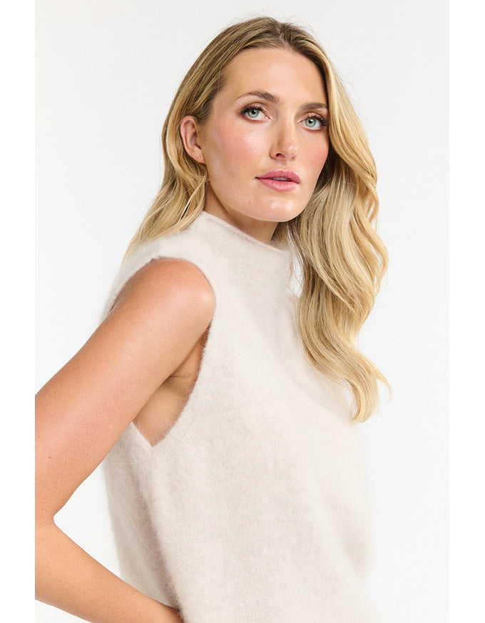 Woman wearing a white sleeveless top against a plain background