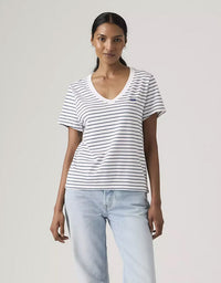 Woman wearing a striped shirt and light blue jeans against a plain background