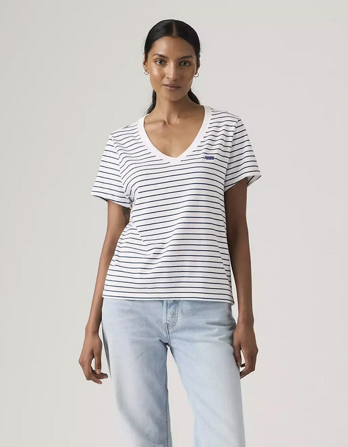Woman wearing a striped shirt and light blue jeans against a plain background