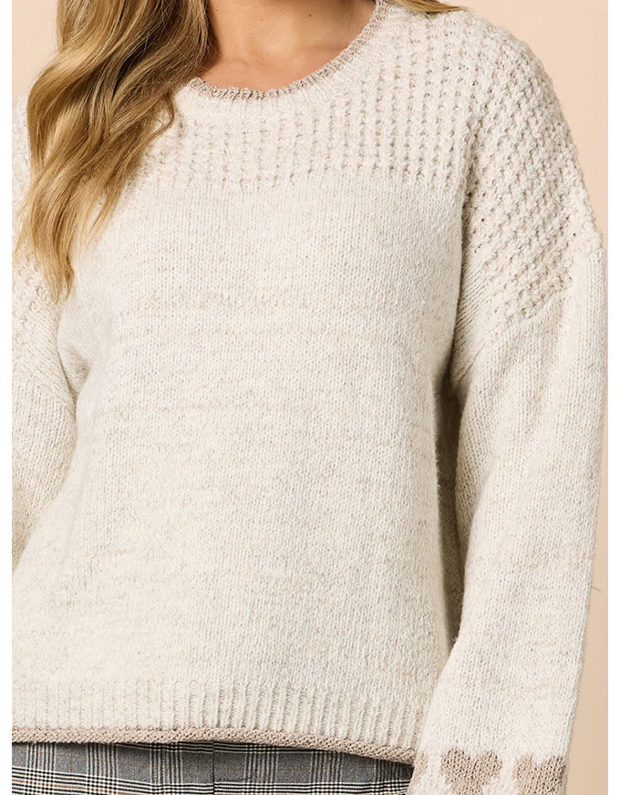 Close-up of a beige knitted sweater worn by a person.