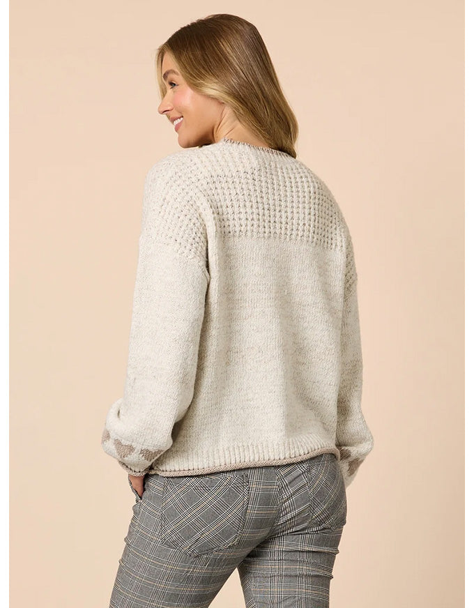Woman wearing a beige knitted sweater and plaid pants on a beige background