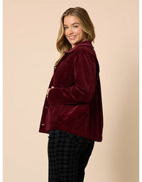 Woman wearing a burgundy velvet jacket on a beige background