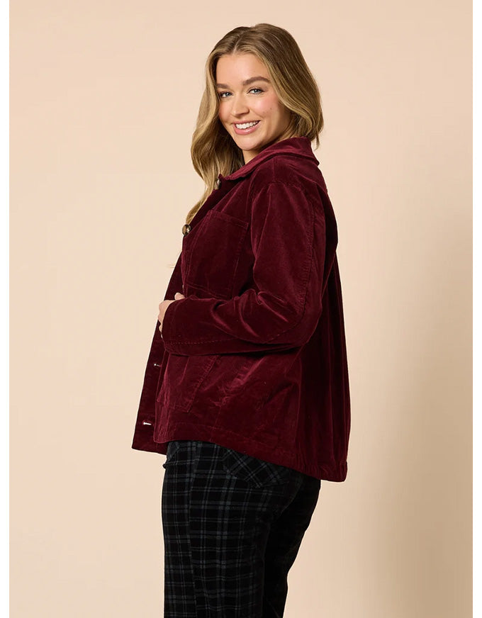 Woman wearing a burgundy velvet jacket on a beige background