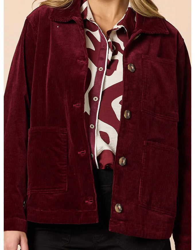 Maroon jacket worn by a person with a patterned shirt underneath on a beige background