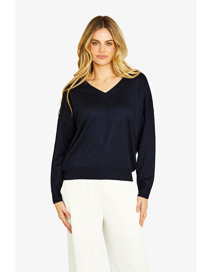 Woman wearing a black sweater and white pants on a white background