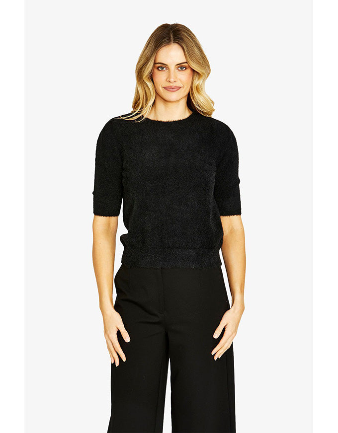 Woman wearing a black sweater and black pants on a white background