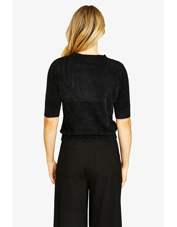 Person wearing a black cropped sweater and pants on a white background