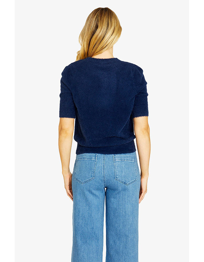 Person wearing a navy sweater and blue jeans on a white background