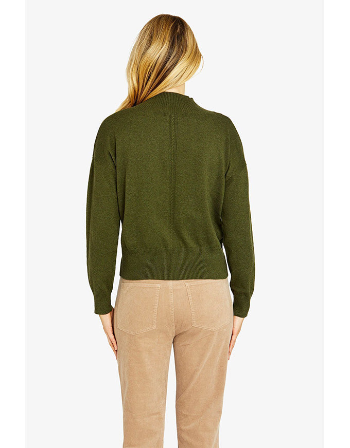 Person wearing a green sweater and beige pants on a white background
