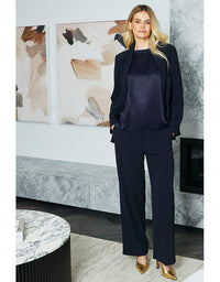 Woman in a navy suit standing in a modern interior setting with abstract art on the wall.