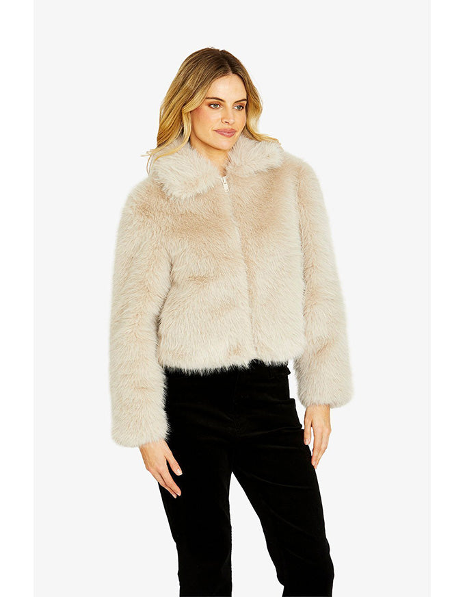 Woman wearing a beige fur jacket on a white background