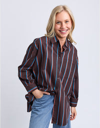 Woman wearing a brown striped shirt and blue jeans on a white background