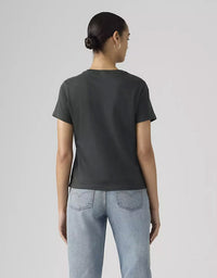 Person wearing a dark gray t-shirt and light blue jeans on a plain background