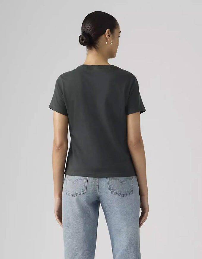 Person wearing a dark gray t-shirt and light blue jeans on a plain background
