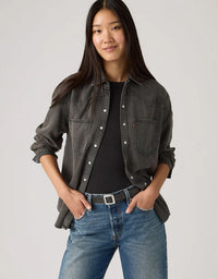 Woman wearing a dark denim shirt and blue jeans on a plain background