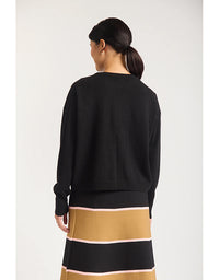 Person wearing a black sweater and a striped skirt with a white background